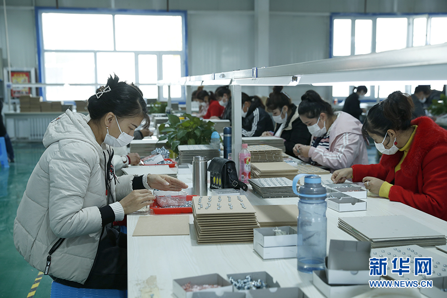 阿図什市阿湖郷就職起業基地で、マイクロイヤホンの生産加工作業に取り組む女性従業員（撮影・焦鵬）。