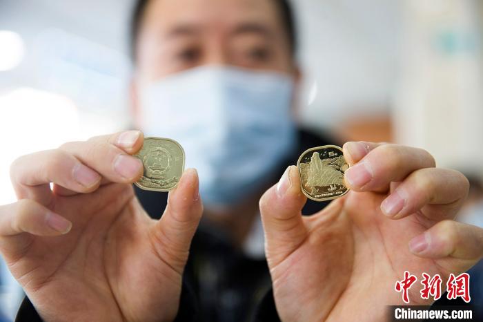 武夷山普通記念貨幣を見せる中国農業銀行職員（撮影・張雲）。