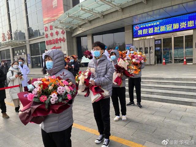 病院のスタッフから贈られた花束を手に、病院から退院した人々。