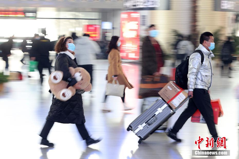 クマのぬいぐるみを抱えたり、キャリーカートの荷物を手に南京鉄道駅構内に移動する乗客（撮影・泱波）。