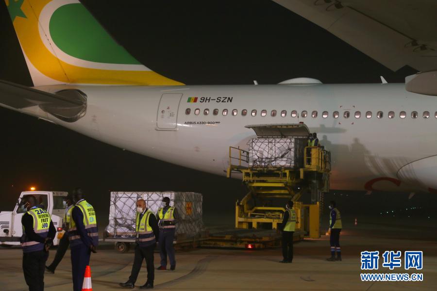 セネガルが中国から輸入した新型コロナウイルスワクチン第1陣を輸送機から降ろす、ブレーズ・ジャーニュ国際空港の職員（撮影・邢建橋）。