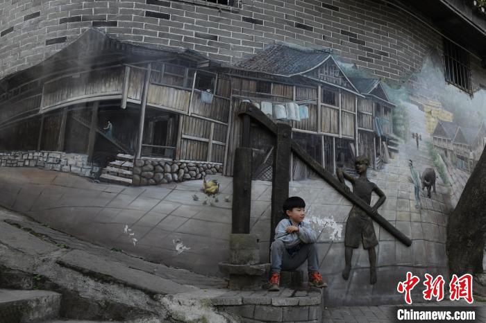 グラフィティアートが施された壁の前にしゃがむ子供（撮影・周毅）。