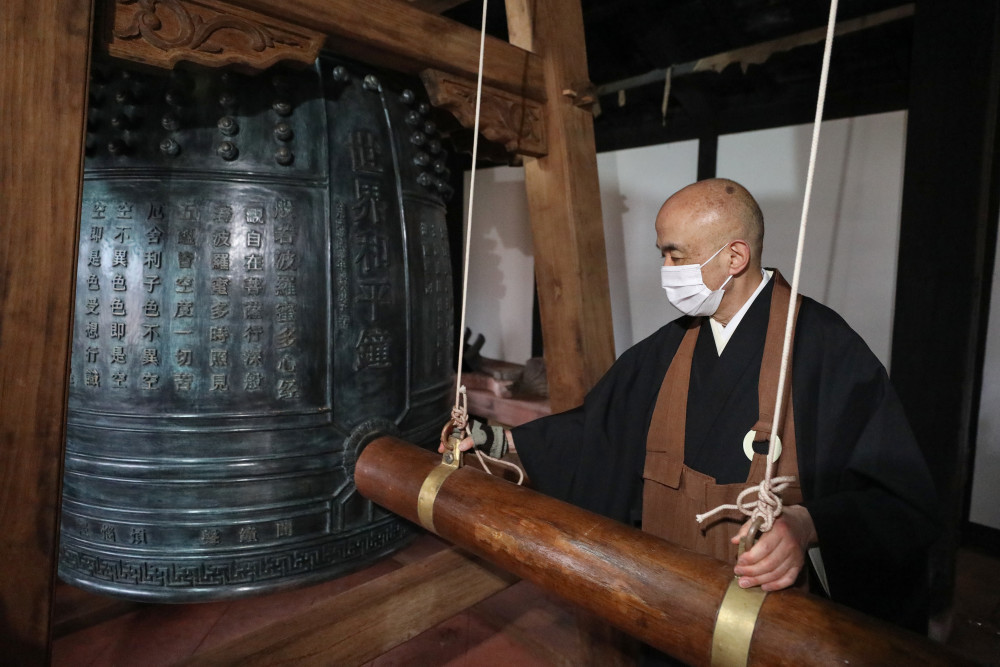 2月26日、長崎興福寺で、「世界平和の鐘」の試し突きをする松尾法道住職（撮影・杜瀟逸）。