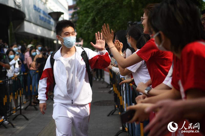 6月7日、北京人民大学附属中学（中高一貫校）の入口で、順序良く試験会場に入る受験生とハイタッチを交わす見送りの人々（撮影・翁奇羽）。