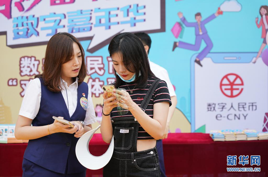 6月16日、来園客の李さんがデジタル人民元ウォレット機能を有効にするプロセスをサポートする交通銀行北京市支店の職員（写真左、撮影・陳鐘昊）。