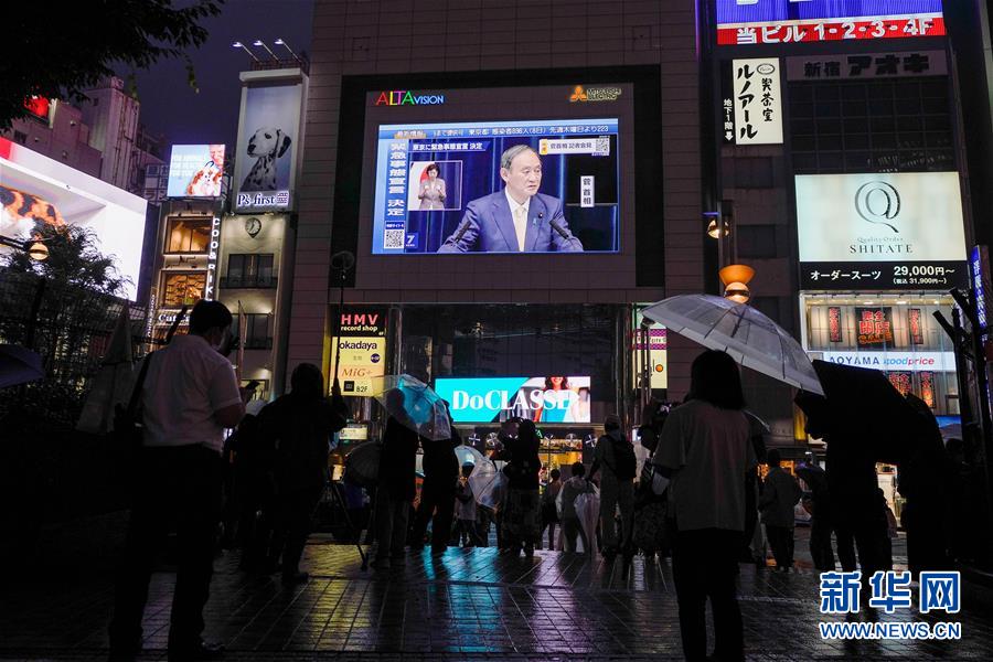 7月8日、日本の東京で、菅義偉首相が緊急事態宣言の発令を表明した記者会見の様子を映し出す街頭スクリーン。