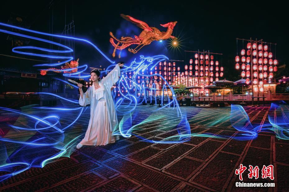 ライトペインティング作品で歌と踊りを披露する漢服姿の女性