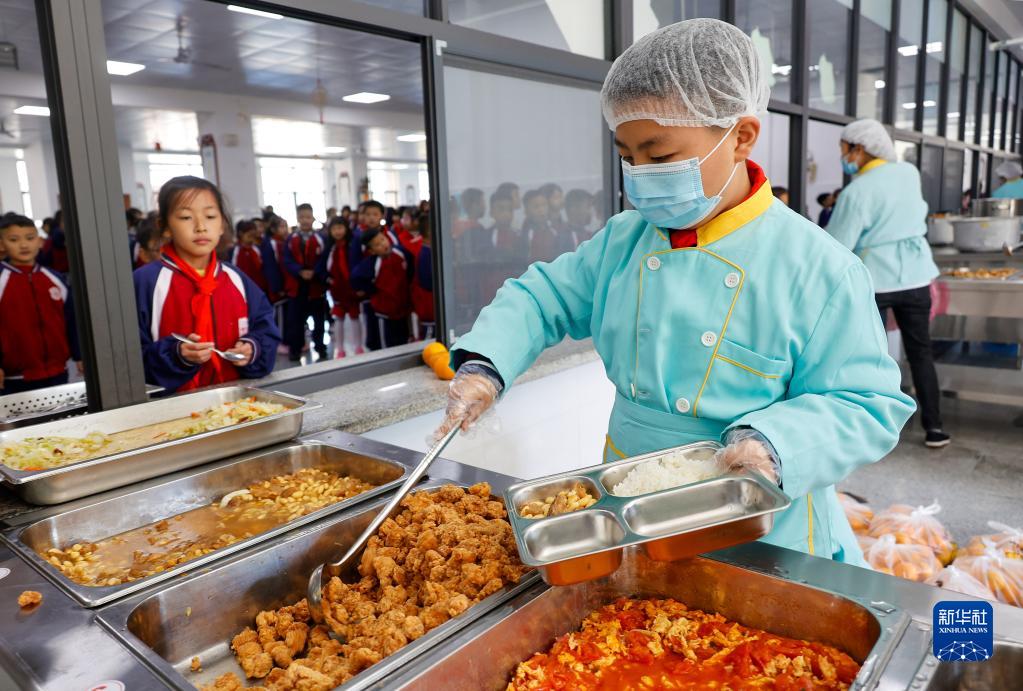 11月10日、紅星小学校食堂の受け取り口で、同級生に食事をとりわける生徒（撮影・李粛人）。