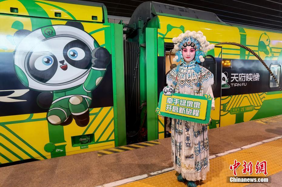 四川省成都市で運行をスタートしたラッピング列車「天府映像」の前で乗客を出迎える川劇の衣装を身につけたスタッフ（11月25日撮影・劉忠俊）。