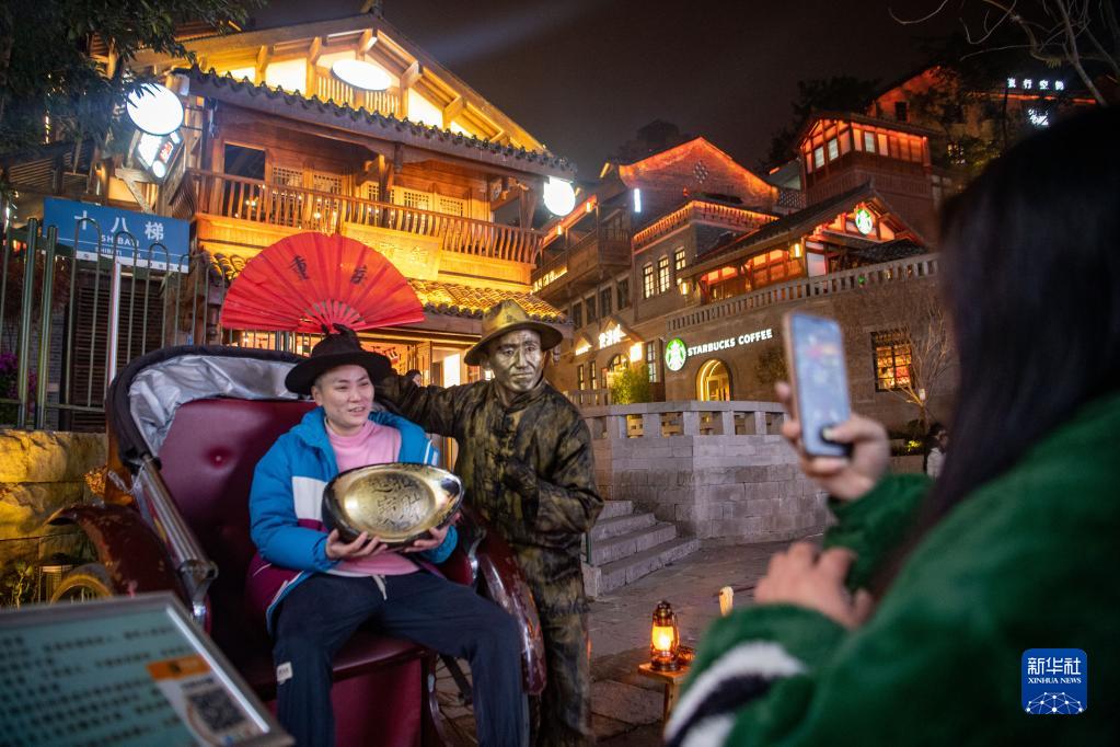 重慶「十八梯」旧市街で、人力車に乗り、銅像に扮した役者と記念写真を撮影する観光客（12月9日撮影・唐奕）。