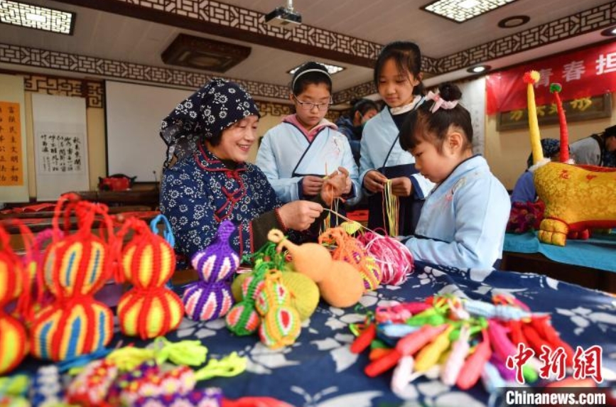 子供たちに手編みヒョウタンの作り方を教える民間工芸の職人（撮影・王海濱）。