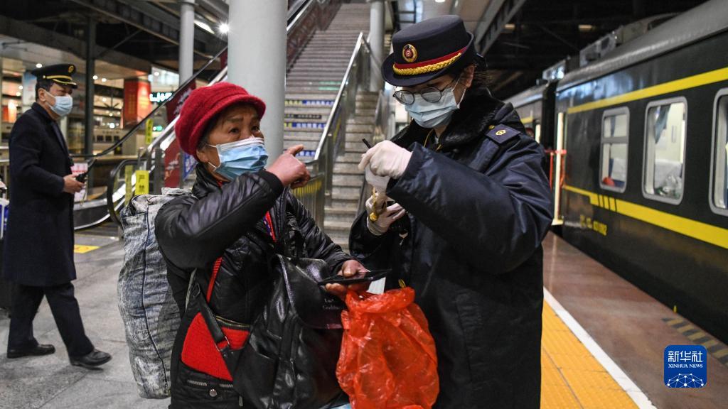 広西壮（チワン）族自治区柳州列車駅で、高齢の乗客からの質問に対応し、スムーズに乗車できるよう手伝う、旅客輸送担当職員の龍澤飛さん（1月24日撮影・張愛林）。