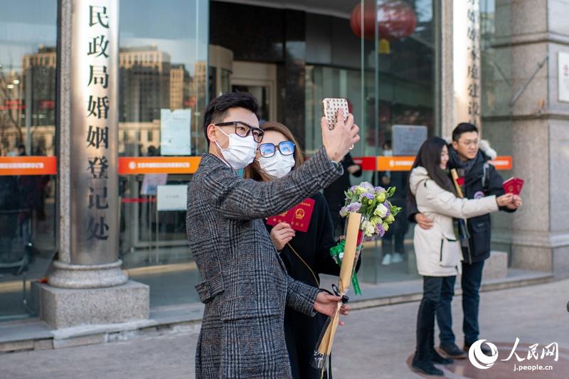 北京市朝陽区民政局婚姻登記処の外で、記念撮影する婚姻届を提出したばかりの新婚カップル（2月22日撮影・翁奇羽）。
