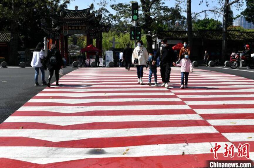 紅白縞模様の横断歩道を渡る市民（撮影・呂明）。