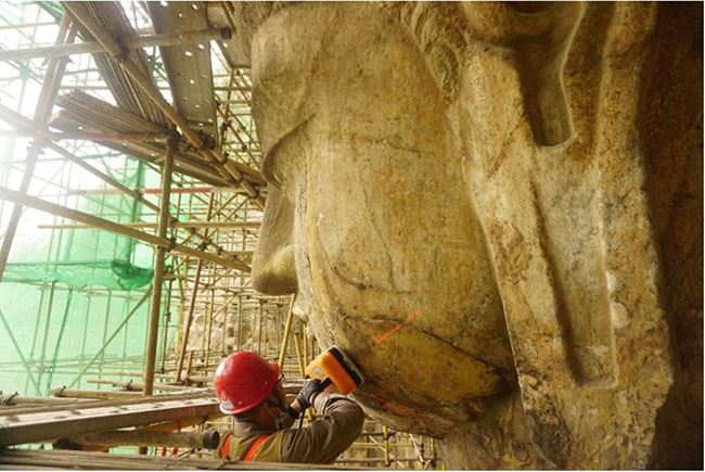 竜門石窟・奉先寺の盧舍那仏の顔面部を調査する考古学者（写真提供・竜門石窟研究院）。
