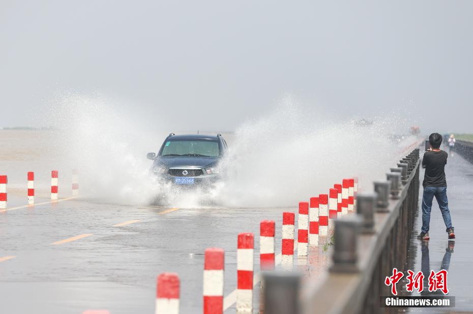 大きな水しぶきをあげながら「水上道路」を走行する自動車（撮影・劉力鑫）。