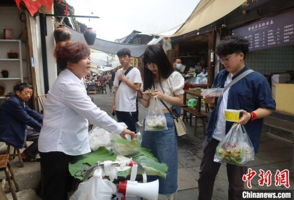 屋台で餅菓子「麻糍」を購入するマカオ出身の学生・程芊慧さん（写真一番右）と同級生（撮影・董易鑫）。