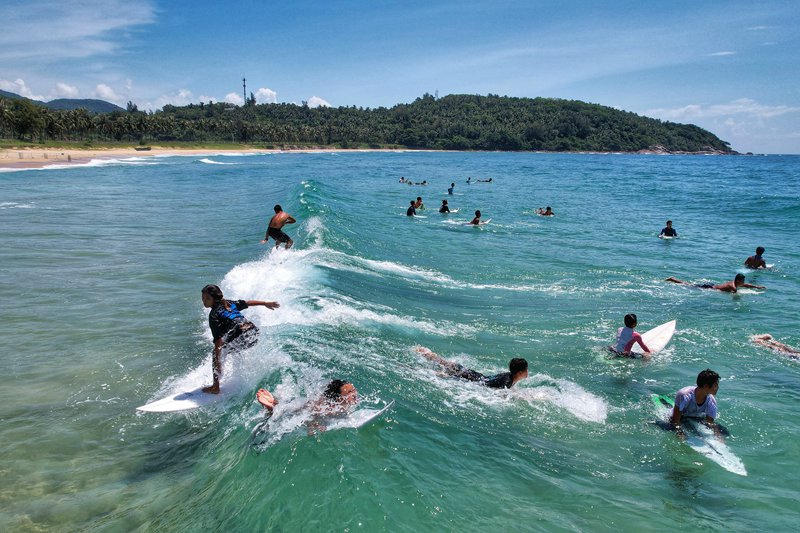 海と空に囲まれ、サーフィンを楽しむ若者たち（写真提供・万寧市観光局）。