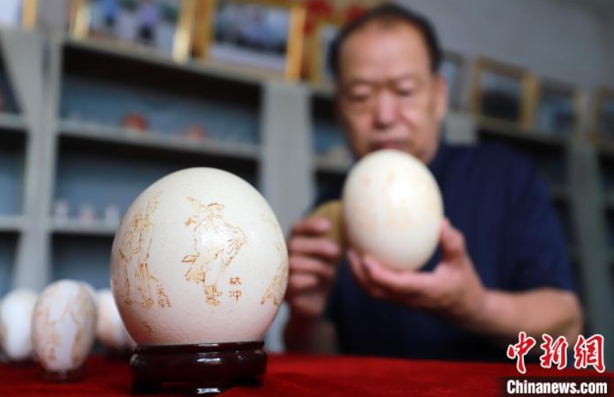 昔から伝わる物語をデザインした卵彫刻作品を整理する鄭青山さん（撮影・薛建東）。