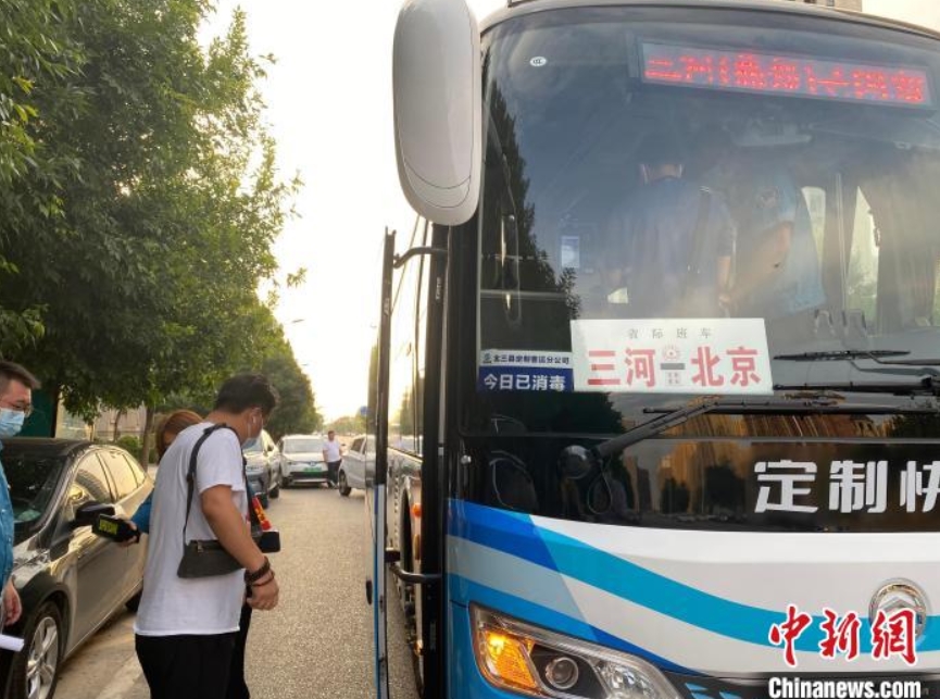7月25日、河北省廊坊市三河市のあるコミュニティ入口で、通勤用カスタマイズ快速バスに乗るため並んで待つ乗客（撮影・高澍）。