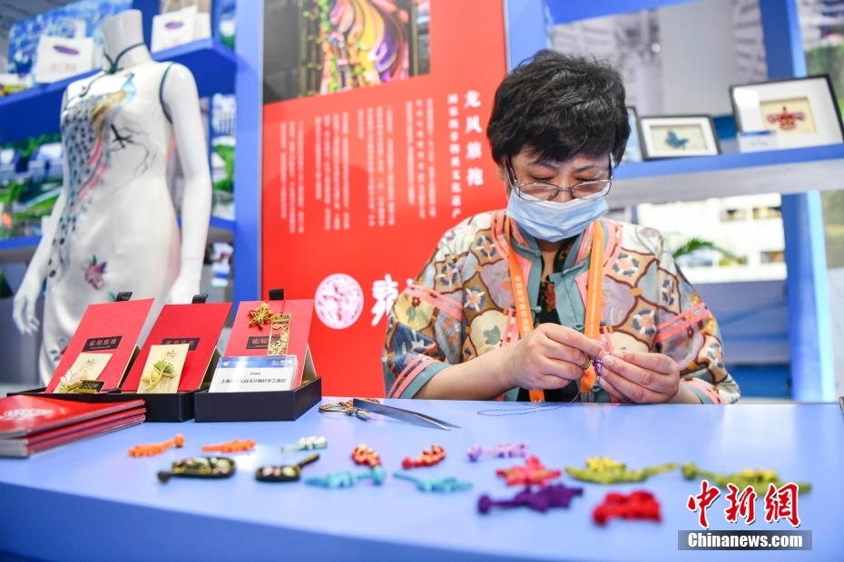 上海館に設けられた中国の老舗チャイナドレスブランド「竜鳳旗袍」展示ブースで、チャイナドレスのボタンの制作技法を披露する無形文化遺産伝承者（撮影・駱雲飛）。