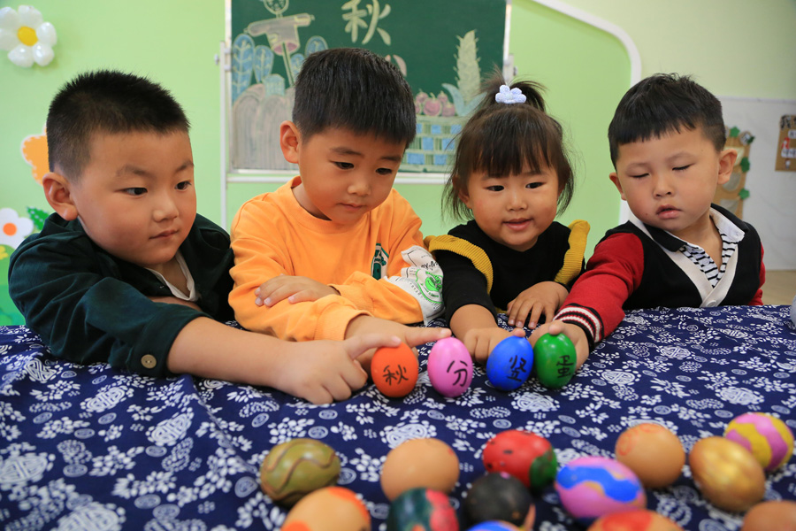 秋分の風俗習慣「卵立て」を体験する子供たち　江蘇省連雲港