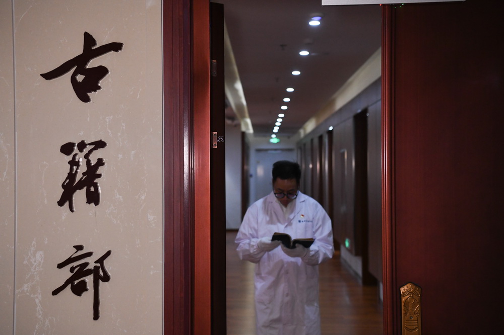 安徽中医薬大学図書館で、修復済の古書を取り出す古書部の鄧勇主任（10月20日撮影・張端）。