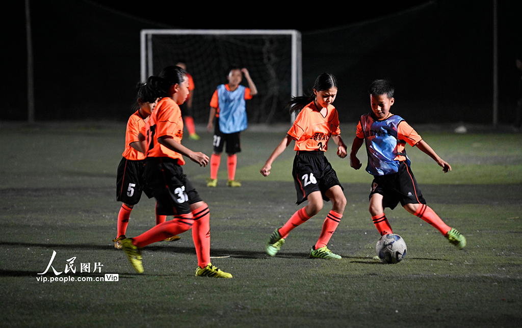 夜間照明に照らされたサッカーグラウンドで練習する農村の子供たち（撮影・黎寒池/写真著作権は人民図片が所有のため転載禁止）。
