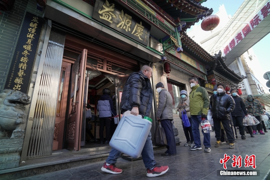 山西省太原市で、大小さまざまな空の容器を手に、黒酢「老陳醋」を買うために列に並ぶ市民（12月26日撮影・武俊傑）。