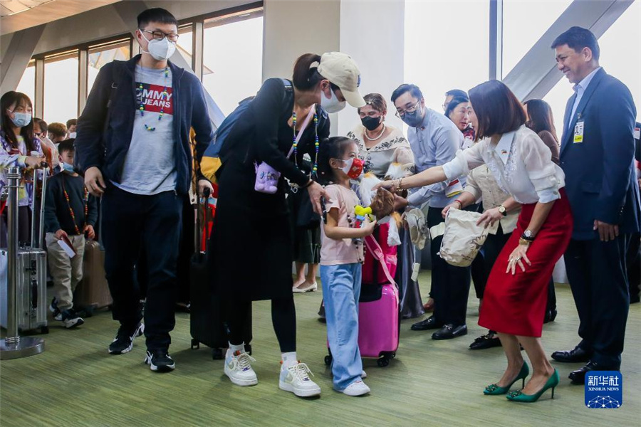 1月24日、フィリピン・マニラのニノイ・アキノ国際空港で、同国のクリスティーナ・ガルシア・フラスコ観光大臣（前方右から2人目）が中国人観光客におみやげを渡した。