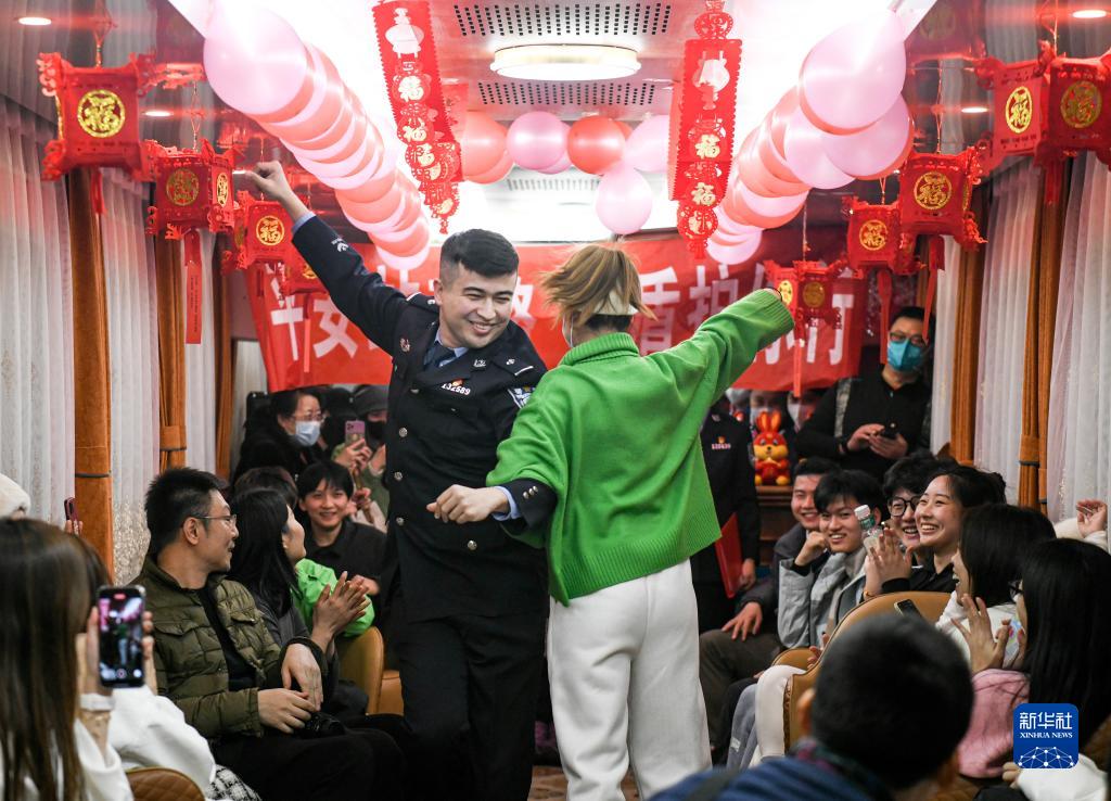 氷雪観光列車「中国雪都－アルタイ号」の車内で、ウイグル族のダンス「麦西来甫」を乗客と一緒に踊る、乗務警察分隊の尼加提·買買堤警官（2月1日撮影・王菲）。