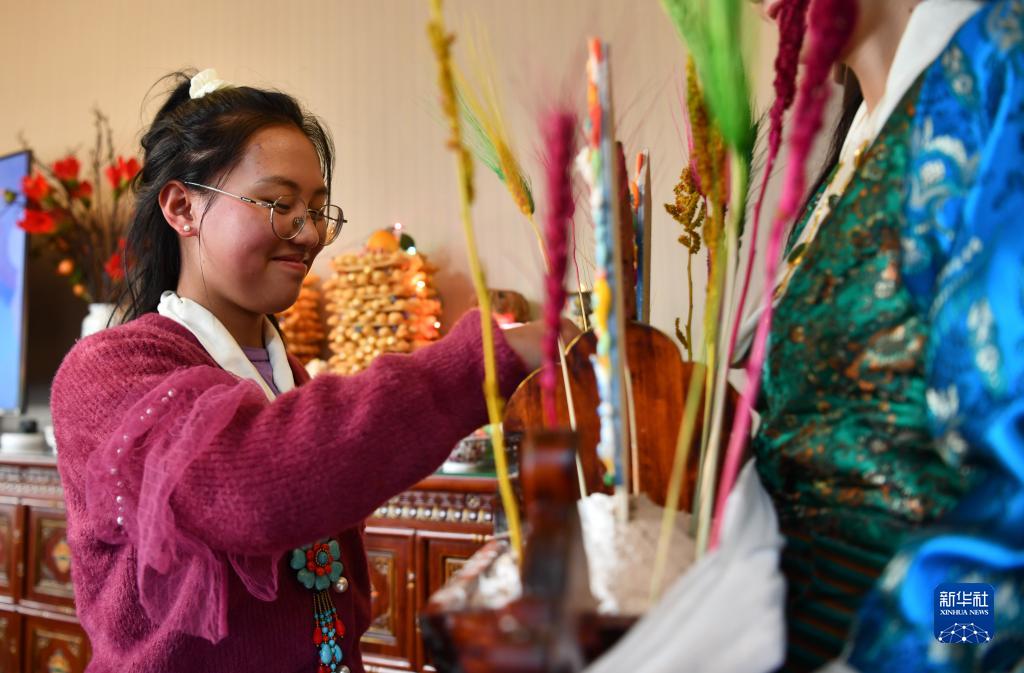 西蔵自治区拉薩(ラサ)市で、蔵族の伝統衣装を着て豊作を願う「切瑪」を食べる女性（2月21日撮影・晋美多吉）。
