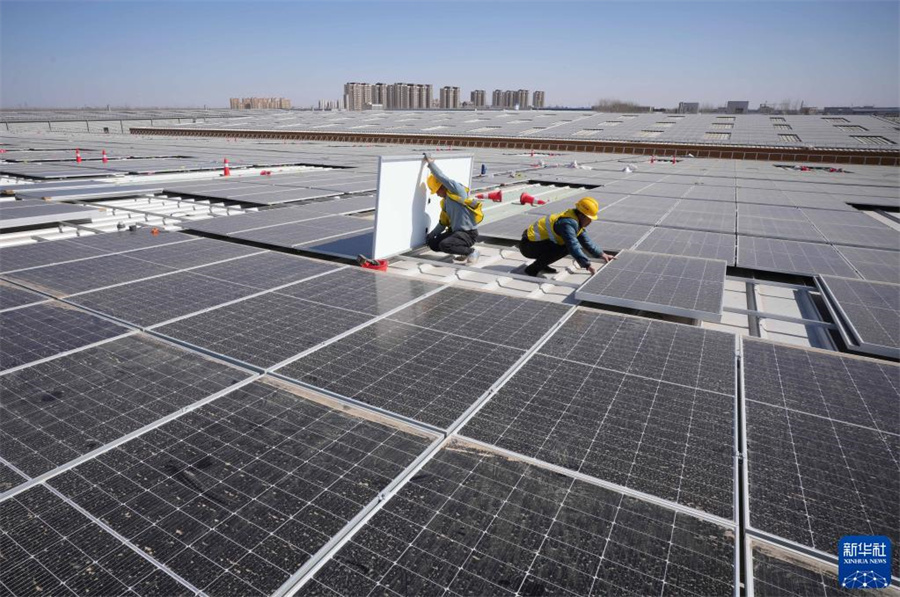 16日、唐山市蘆台経済開発区のある企業の工場の屋上にソーラーパネルを設置する作業員。