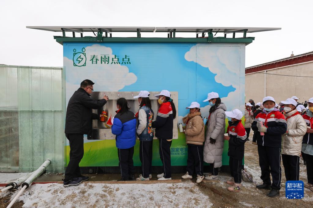 新たに設けられた浄水ステーションの前に並び、飲用水を汲む那曲市色尼区の香茂郷小学校の児童たち（3月21日撮影・姜帆）。