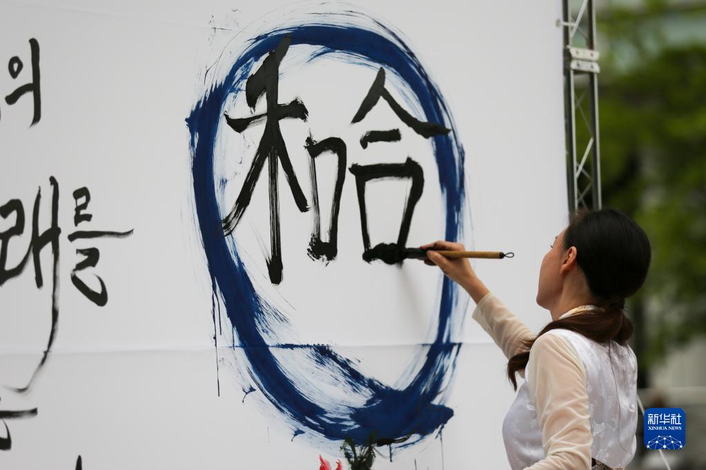 中日韓の精神である2023年度の漢字「和合」を毛筆で書く女性（撮影・王益亮）。