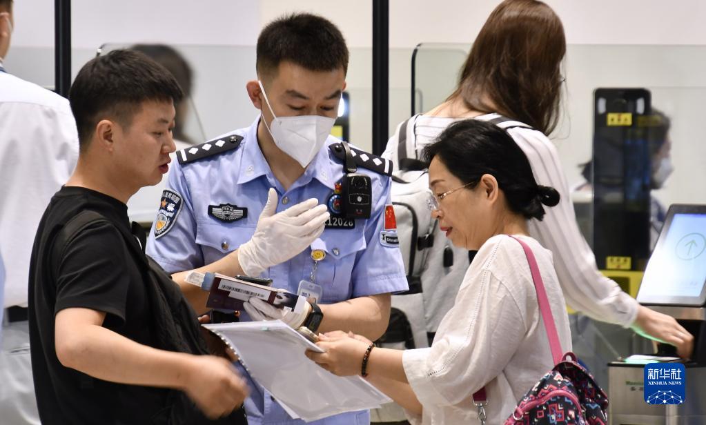 首都国際空港出入境辺防検査ステーションで、出国する旅客からの問合せに答える警察官（6月1日撮影・李欣）。