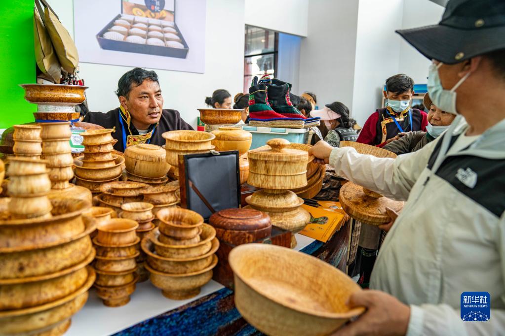 第5回中国西蔵観光文化国際博覧会の会場で、木製のボウルを来場者に紹介する職員（6月17日撮影・孫非）。
