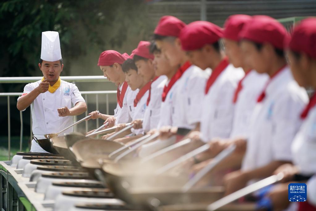 陝西省西安市藍田県にある藍田厨師学校で、フライ返しの扱い方を指導する成暁強先生（写真左、6月25日撮影・李一博）。