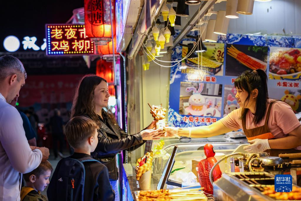 琿春市漢唐街のナイトマーケットで、グルメを買い求めるロシア人観光客（6月27日撮影・顔麟蘊）。