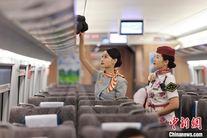 一緒に車両内の荷物棚を整理する重慶旅客運輸区間の乗務員と西方航空の客室乗務員（撮影・蘇志剛）。