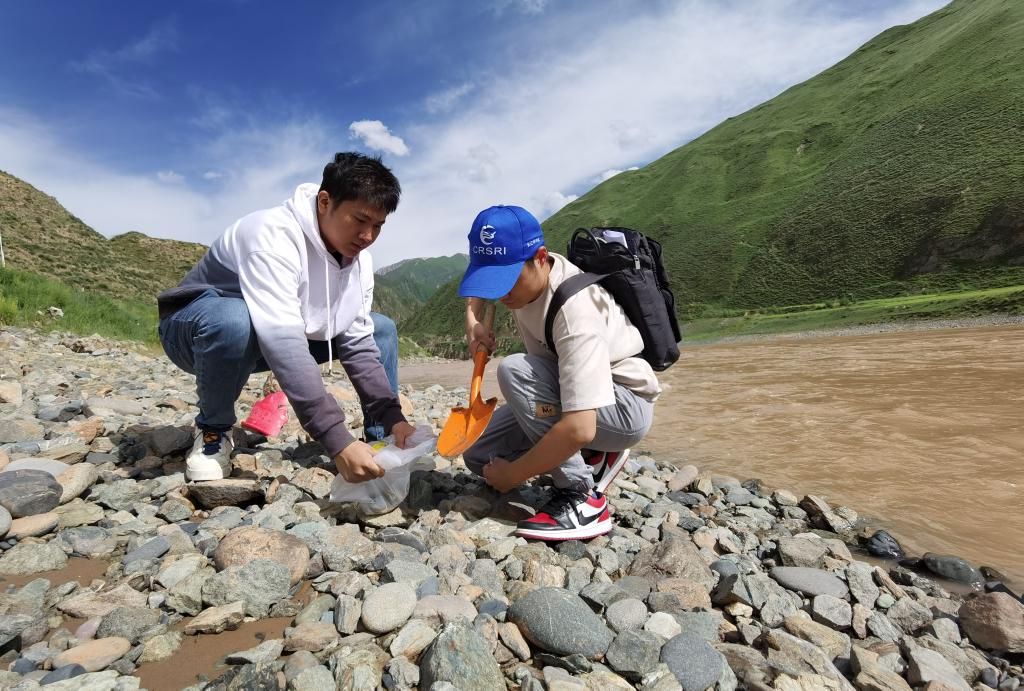 長江科学院河流研究所の科学調査隊員の徐志成氏（左）が22日、通天河直門達区間で川底の泥砂を採取した。撮影・李勁峰