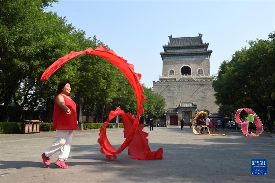 北京の鐘楼の前の広場で踊る女性（7月18日撮影）。北京中軸線の最北端に位置する700年以上の歴史を誇る鐘楼と鼓楼は、南北に並んで配置され、雄大な姿を見せている。元、明、清の3つの時代にわたって、北京の人々に時を知らせてきた。
