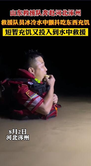 寸暇惜しみ冷たい水に浸かったまま食べ物を口にする救助隊員　河北省涿州