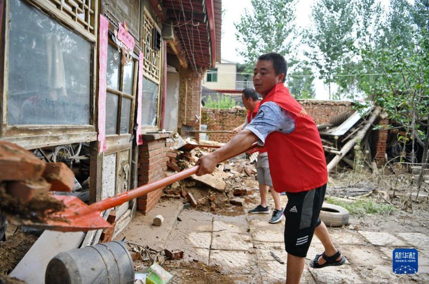 8月6日、河北省涿洲市刁窩鎮白塔村で、洪水によって損壊した民家の前で瓦礫を片付けるボランティア（撮影・牟宇）