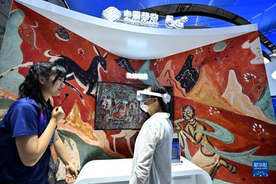 首鋼パーク会場の中国移動（チャイナ・モバイル）ブースで、拡張現実（AR）/仮想現実（VR）技術を利用した敦煌の特殊効果ガイドを体験する来場者。