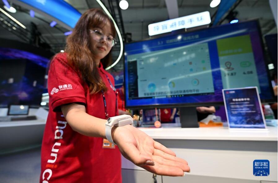 9月3日、首鋼パーク会場の中国聯通（チャイナ・ユニコム）ブースで、超音波技術を利用して障害物を検出する視覚障害者用ブレスレットを紹介するスタッフ。