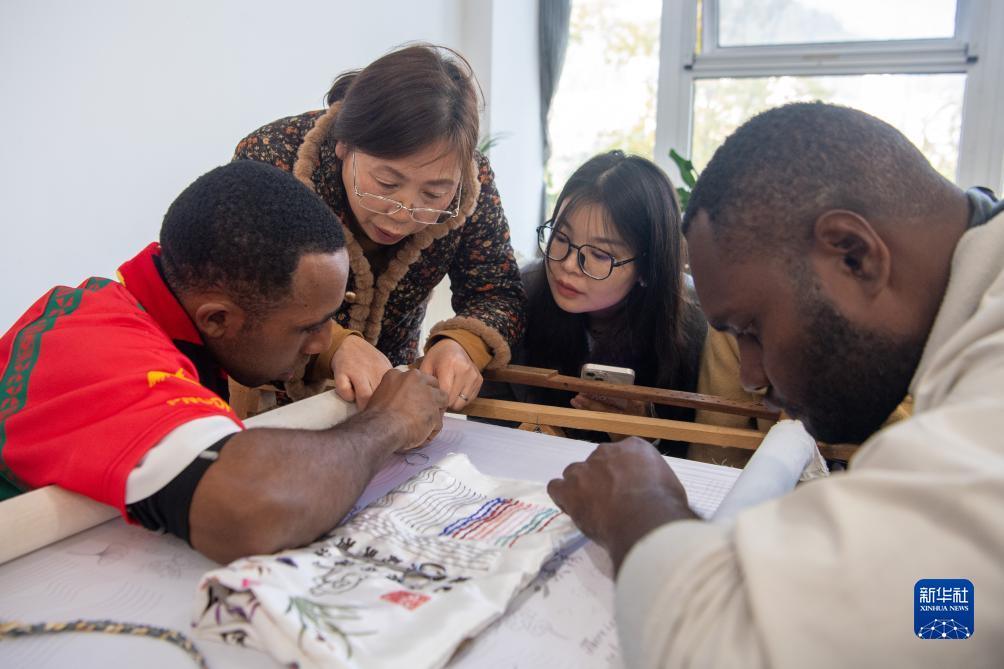重慶市万州区の三峡秀工房で、技術者の指導を受けながら三峡の刺繍を体験するパプアニューギニアの学生（11月27日撮影・唐奕）。