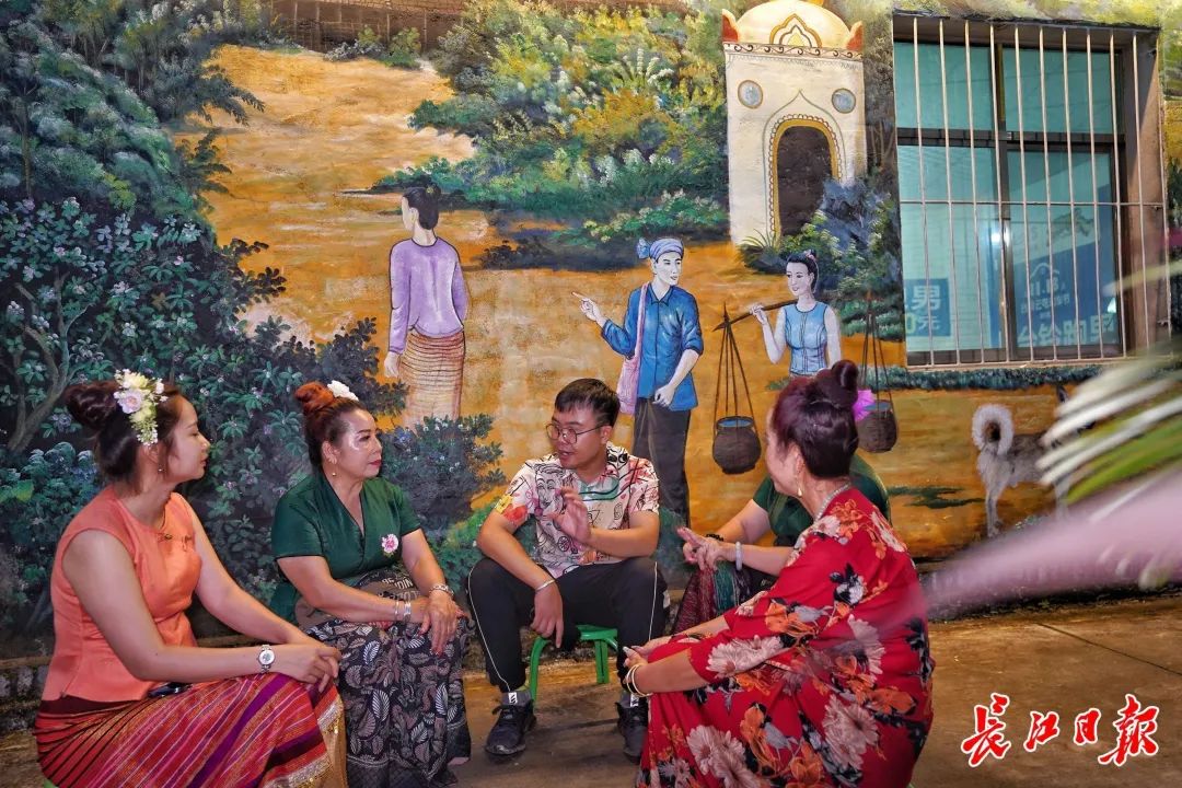 壁画のインスピレーションを得るために村の女性から傣族の伝統的な民話を聞く岩さん。