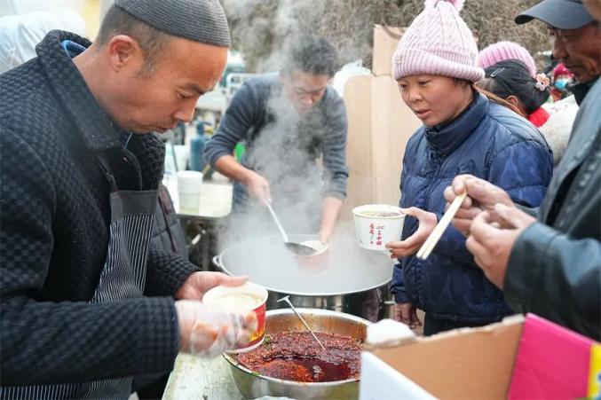 避難所の炊きだしでラーメンを提供する男性たち（撮影・賀勇）。