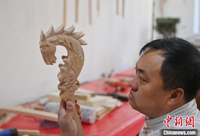 干支の竜を彫刻した馬頭琴を制作する白蘇古郎さん（撮影・張瑶）。